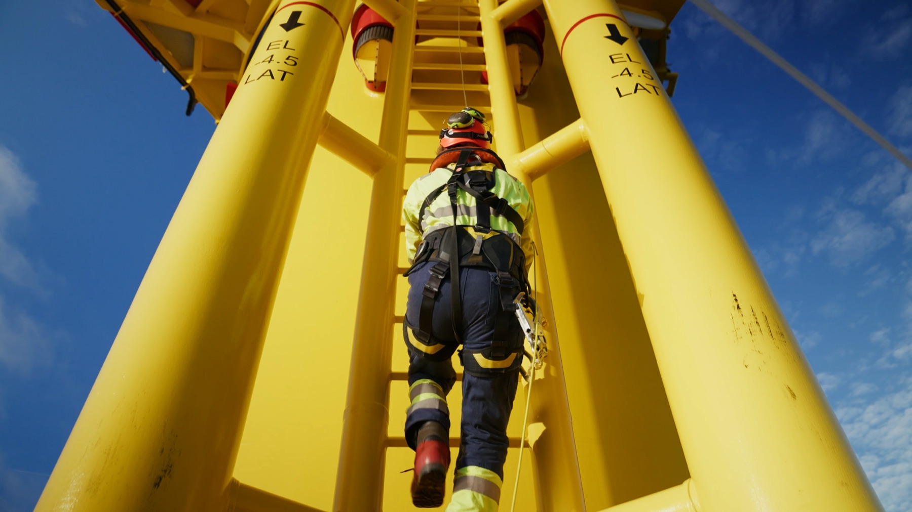 Technician climbing a turbine boat-landing ladder